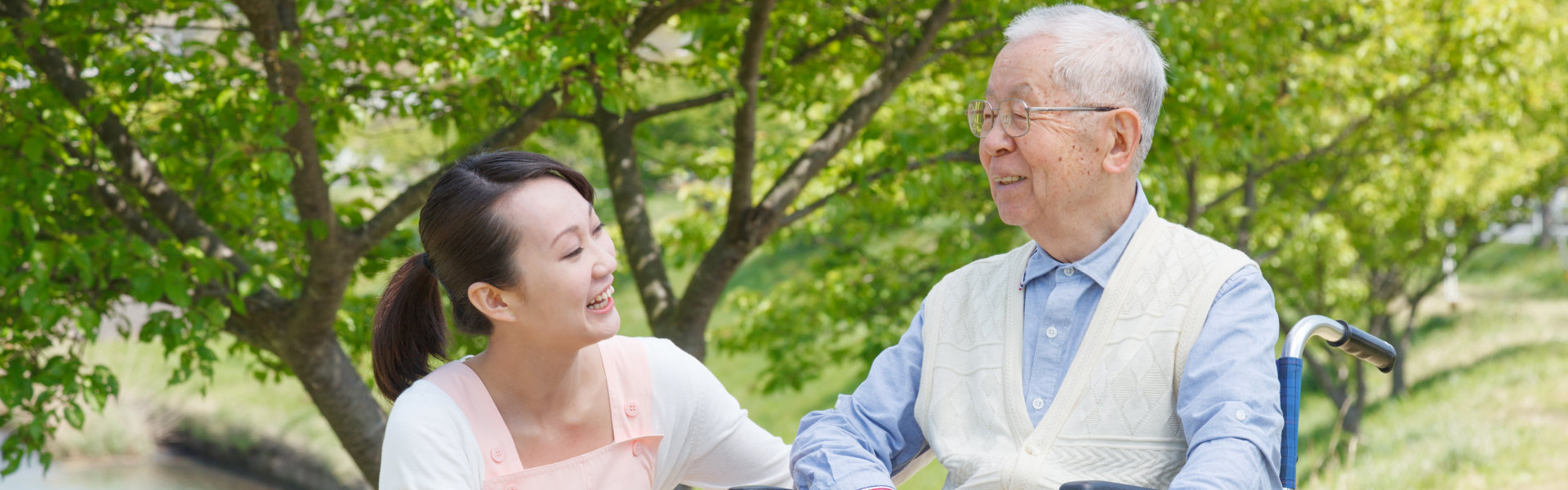 caregiver and elderly man in a wheelchair smiling